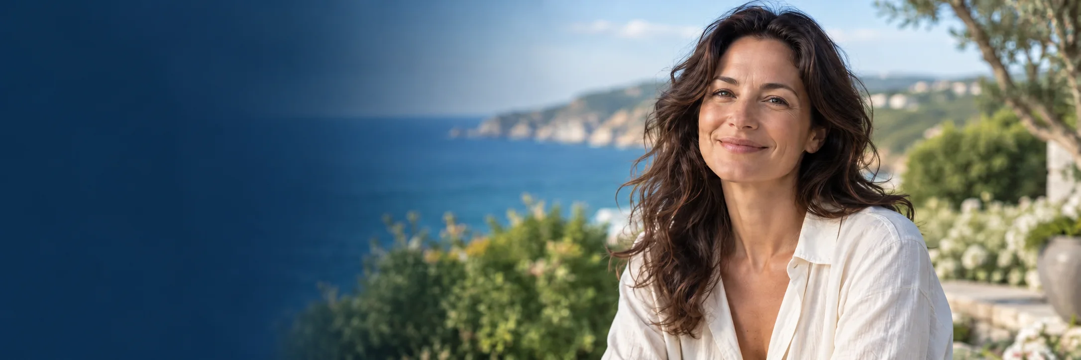 Smiling woman in a white linen shirt on a garden terrace overlooking the sea