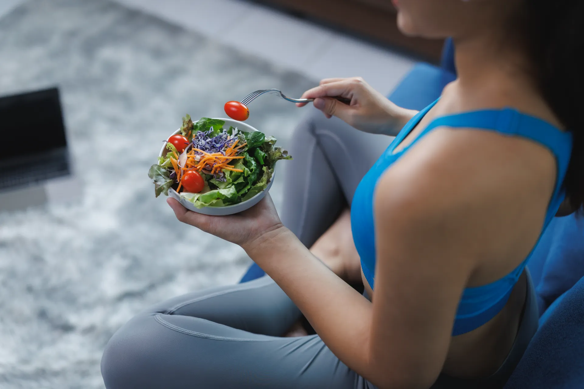 young woman eating healthy salad after workout at utc